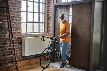 Älterer Mann mit Fahrrad bei der Ankunft zu Hause - FMKF07415