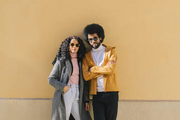Couple wearing sunglasses standing in front of wall - MMPF00006