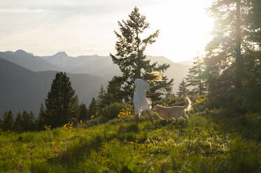 Female in dress posing with their dog with mountain views - CAVF96215