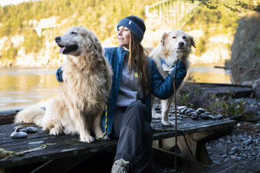 Frau sitzt auf einem Picknicktisch mit Hunden im Deception Pass State Park - CAVF96218