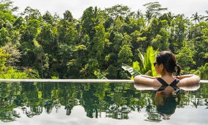 Frau genießt die Aussicht vom Infinity-Pool eines Resorts in Bali - CAVF96257