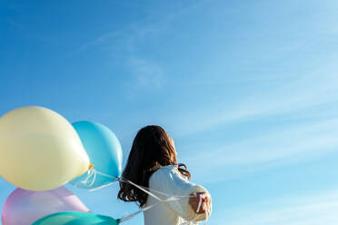 Anonyme junge Frau, die mit bunten Luftballons spielt - CAVF96269