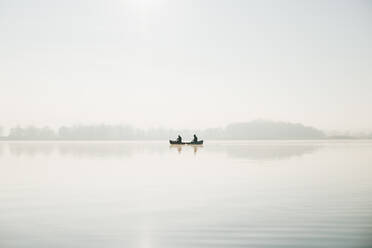 Zwei Männer in einem Kanu auf der weiten ruhigen Wasseroberfläche des Sees, sonniger Tag - CAVF96282