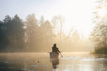 A canoe boat on the river, sun shining through the morning mist - CAVF96284