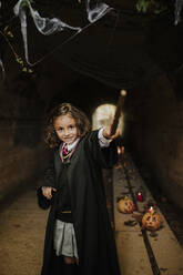Smiling girl wearing witch costume having fun in tunnel at Halloween - GMLF01288