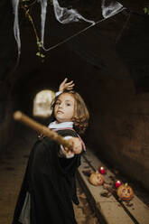 Girl wearing witch costume having fun in spooky tunnel at Halloween - GMLF01289