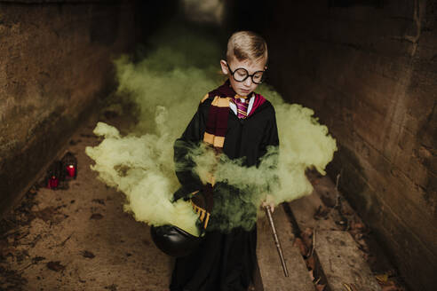 Boy with cauldron and magic ward standing amidst yellow in tunnel - GMLF01307