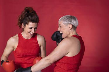 Happy friends with boxing gloves standing against red background - EIF04011