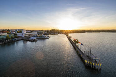 Deutschland, Baden-Württemberg, Friedrichshafen, Luftaufnahme der Stadt am Bodenseeufer bei Sonnenaufgang mit langer Seebrücke im Vordergund - WDF06923