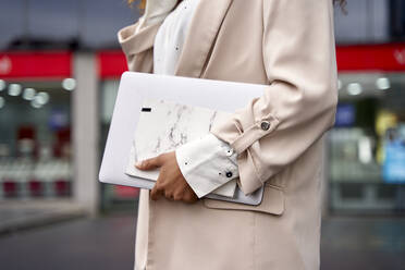 Hands of businesswoman holding notebook and laptop - VEGF05580