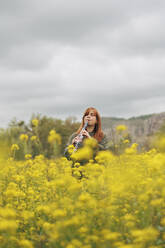 Klarinette spielende Frau in einem Blumenfeld stehend - MRRF02039