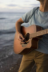 Mann spielt Gitarre am Strand - SSGF00835