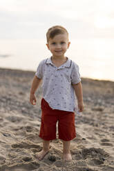 Smiling baby boy standing at beach - SSGF00839