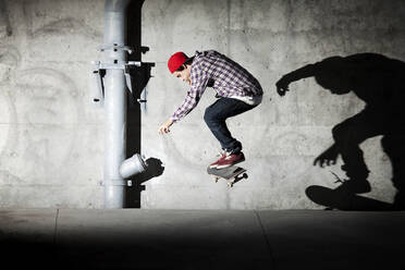 Skateboarder unter einer Überführung mit Schatten an der Wand - CAVF96304