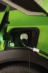 Electric car being charged by plug at charging station - GMCF00289