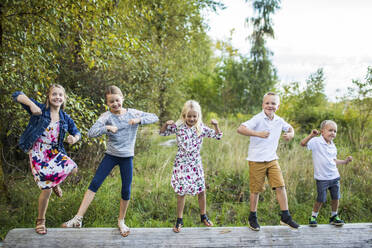 Five cute kids dancing outdoors on log - CAVF96349