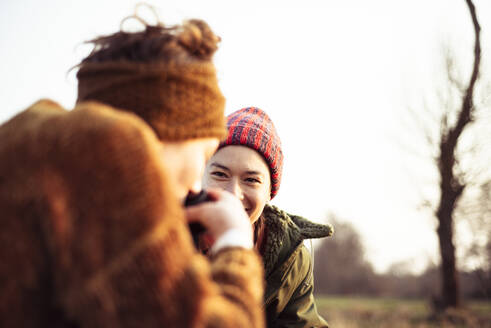 Freunde lachen und trinken Tee in der Wintersonne Picknick auf dem Feld - CAVF96395