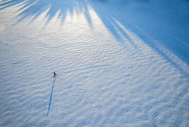 Tiny figure and shadow of lone skier on frozen lake, Maine - CAVF96463