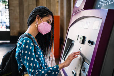 Hispanic woman in medical mask buying ticket in railway station - CAVF96470