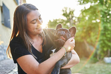 Young woman and her dog in the garden at sunset - CAVF96482