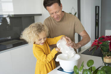 Lächelnder Vater und Tochter backen zusammen in der Küche zu Hause - SVKF00136