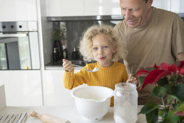 Glückliches blondes Mädchen backt mit ihrem Vater in der Küche zu Hause - SVKF00141