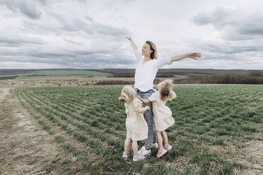 Carefree woman with arms outstretched standing with daughter in agricultural field - SIF00087