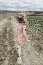 Girl running on dirt road in agricultural field - SIF00089