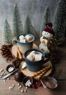 Tassen mit heißem Kakao und Marshmallows, umgeben von winterlichen Dingen. - CAVF96489