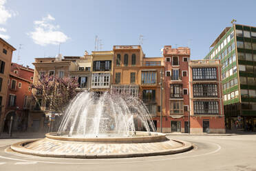 Spain, Balearic Islands, Palma, Traffic circle fountain with row houses in background - FCF02035