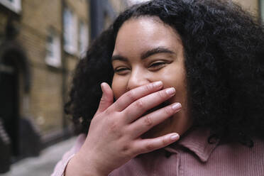 Cheerful young woman laughing with hand covering mouth - ASGF02282