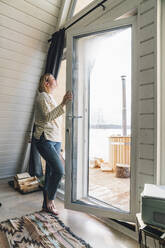 Woman inhaling fresh air opening glass door at home - VPIF05939