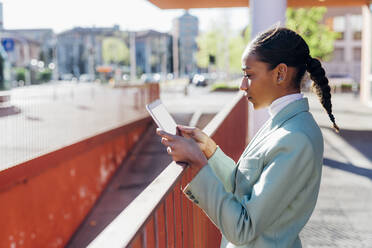 Businesswoman using tablet computer on footpath - MEUF05252