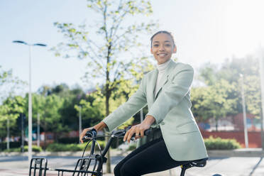 Young businesswoman riding electric bicycle on street - MEUF05264