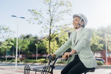 Happy businesswoman cycling on street - MEUF05266