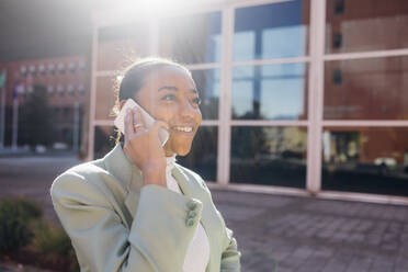 Happy businesswoman talking over mobile phone on sunny day - MEUF05282