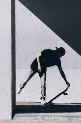 Mann auf dem Skateboard vor einer Mauer - OMIF00764