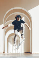 Mann mit Skateboard springt in Spielhalle - OMIF00775