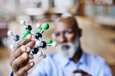 Scientist holding molecular structure at home - FMKF07508