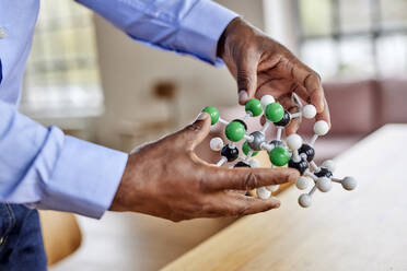 Scientist holding molecular structure at home - FMKF07522