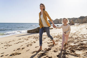 Happy mother with daughter walking on shore at beach - DIGF17848