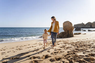 Mother with daughter walking on shore at beach - DIGF17849