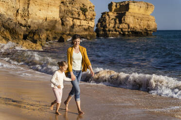 Lächelnde Frau, die mit ihrer Tochter am Strand spazieren geht - DIGF17855