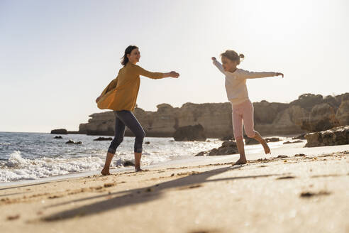 Glückliche Mutter und Tochter spielen am Strand - DIGF17871