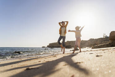 Happy mother and daughter enjoying at beach on sunny day - DIGF17872