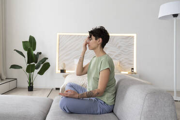 Frau meditiert auf dem Sofa sitzend zu Hause - VPIF06005