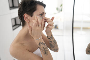 Woman applying eye mask in bathroom at home - VPIF06021