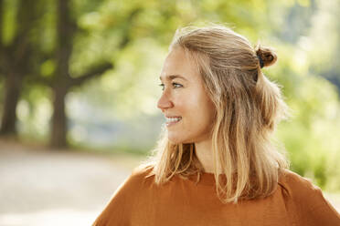 Lächelnde blonde Frau schaut im Park weg - JHAF00148