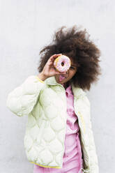Girl looking through doughnut in front of wall - PNAF03791