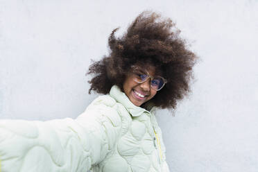 Lächelndes Afro-Mädchen, das ein Selfie vor einer weißen Wand macht - PNAF03803